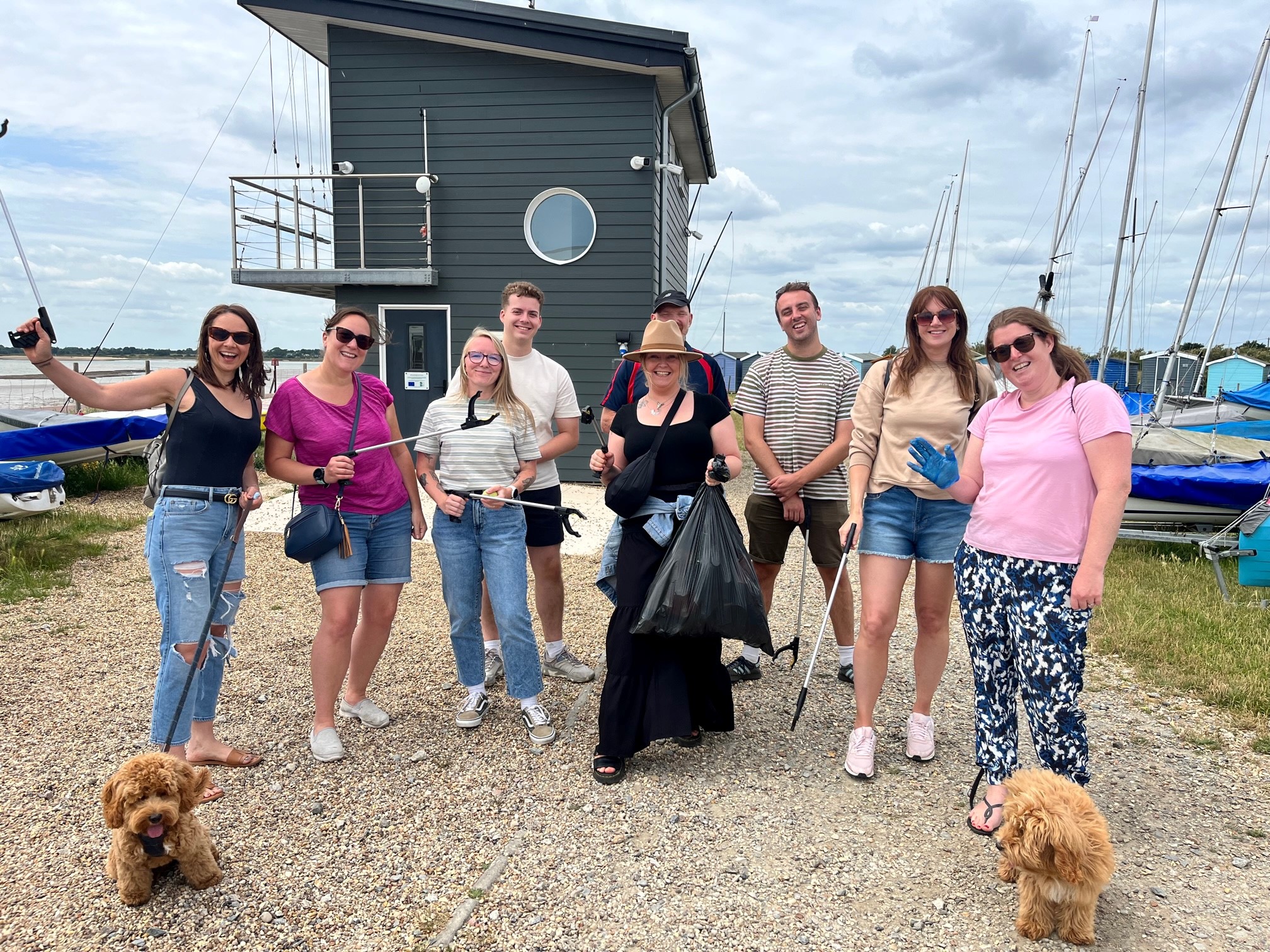 A group of men and women and dogs posing at a beach.