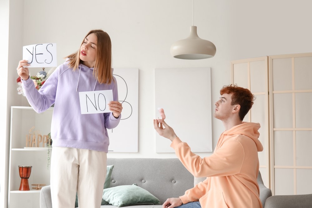 Yopung man proposing to a young girl, whois holding up yes and no signs