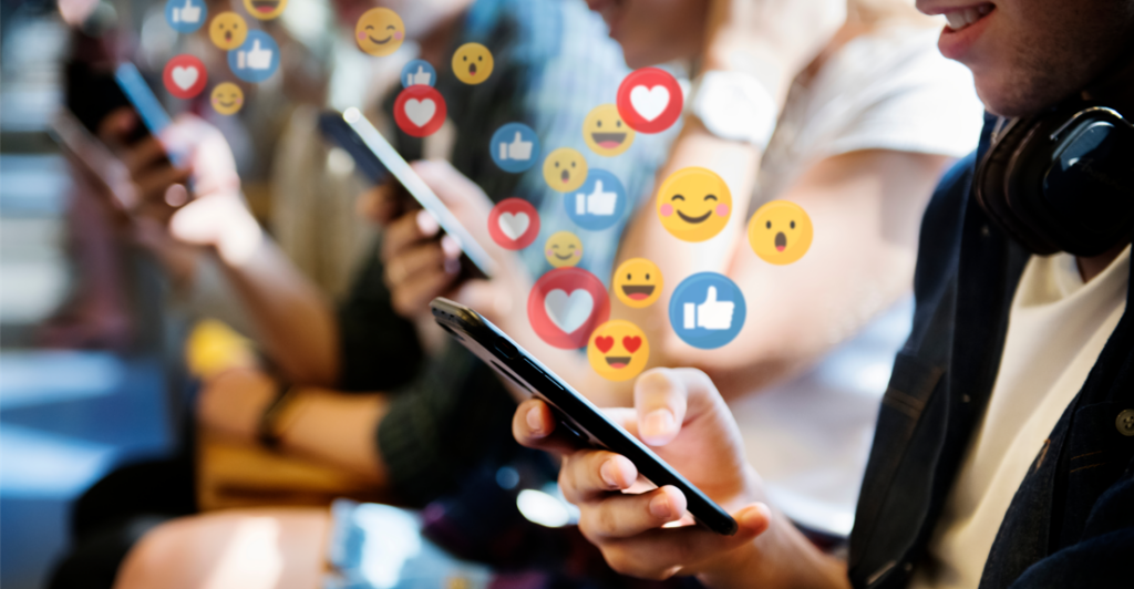 People using social media with emojis bubbling out of their devices