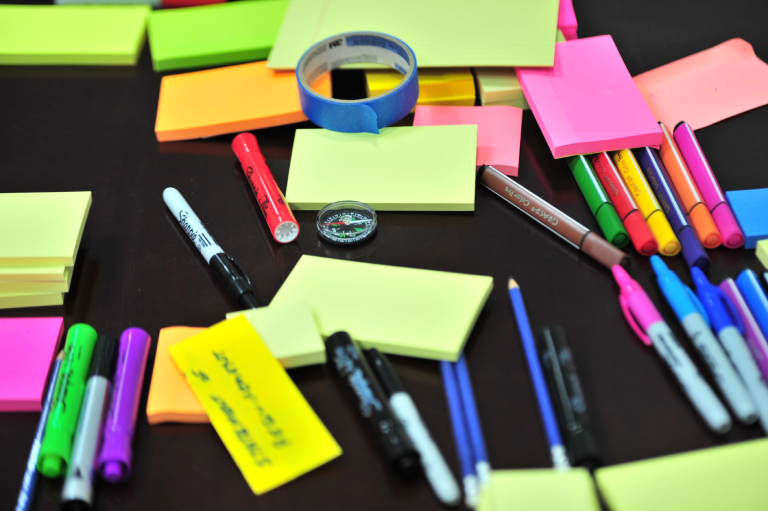 Stationary-post-it-notes-and-marker-pens-on-a-black-table-cloth.