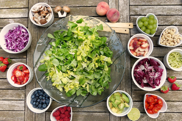 Colourful salad, fruits and vegetables laid on a wooden table.