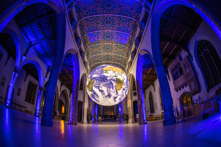 Projection of Gaia, floating the middle of the Cathedral. Backlit by blue projection light.